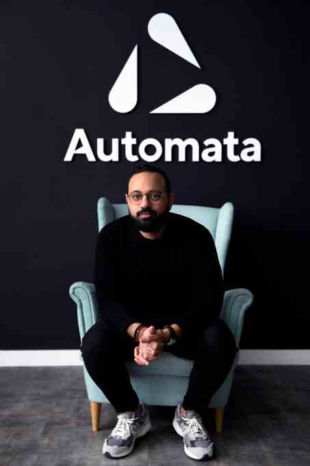 CEO Mostafa ElSayed sitzt auf einem Stuhl unter dem Automata-Logo.