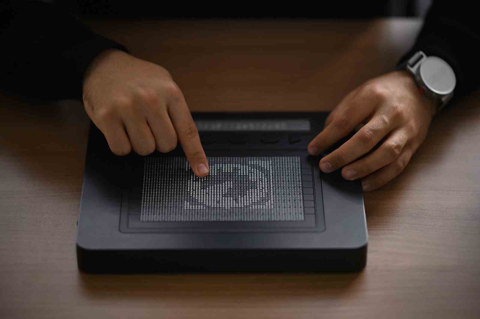 Die Hände einer Person berühren ein Bild eines Globus, der in Stecknadeln auf einem Dotpad angezeigt wird.