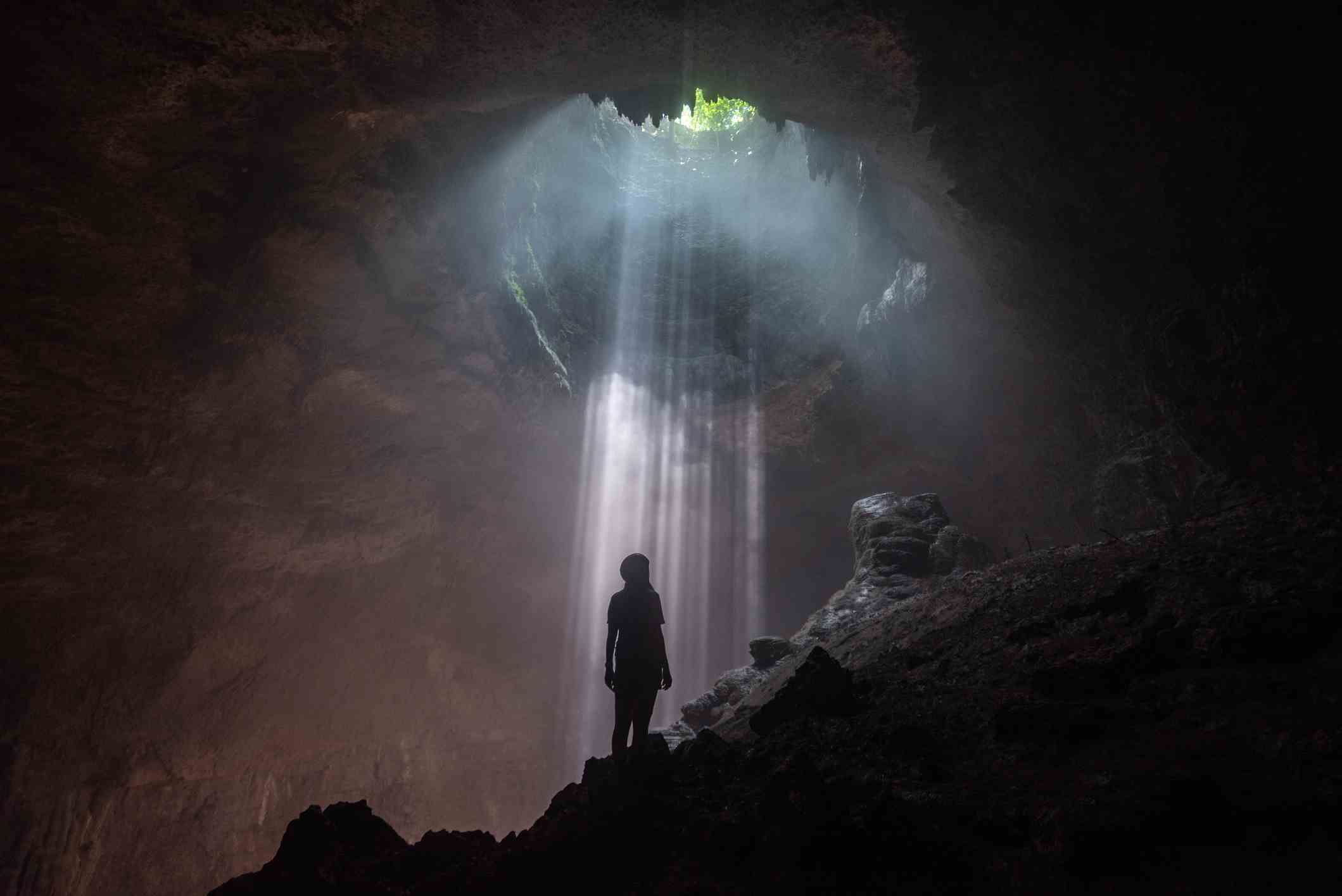 Frau, die zur Öffnung in der Jomblang-Höhle aufblickt