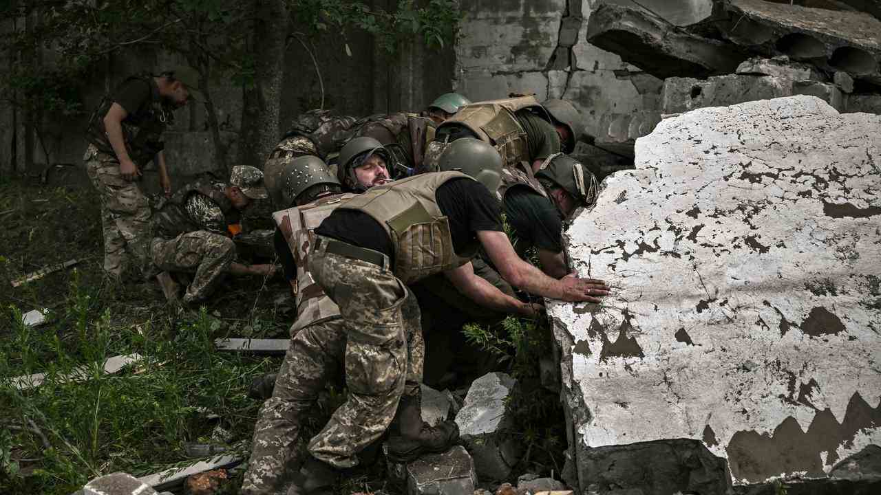 Ukrainische Soldaten untersuchen ein zerbombtes Lagerhaus.