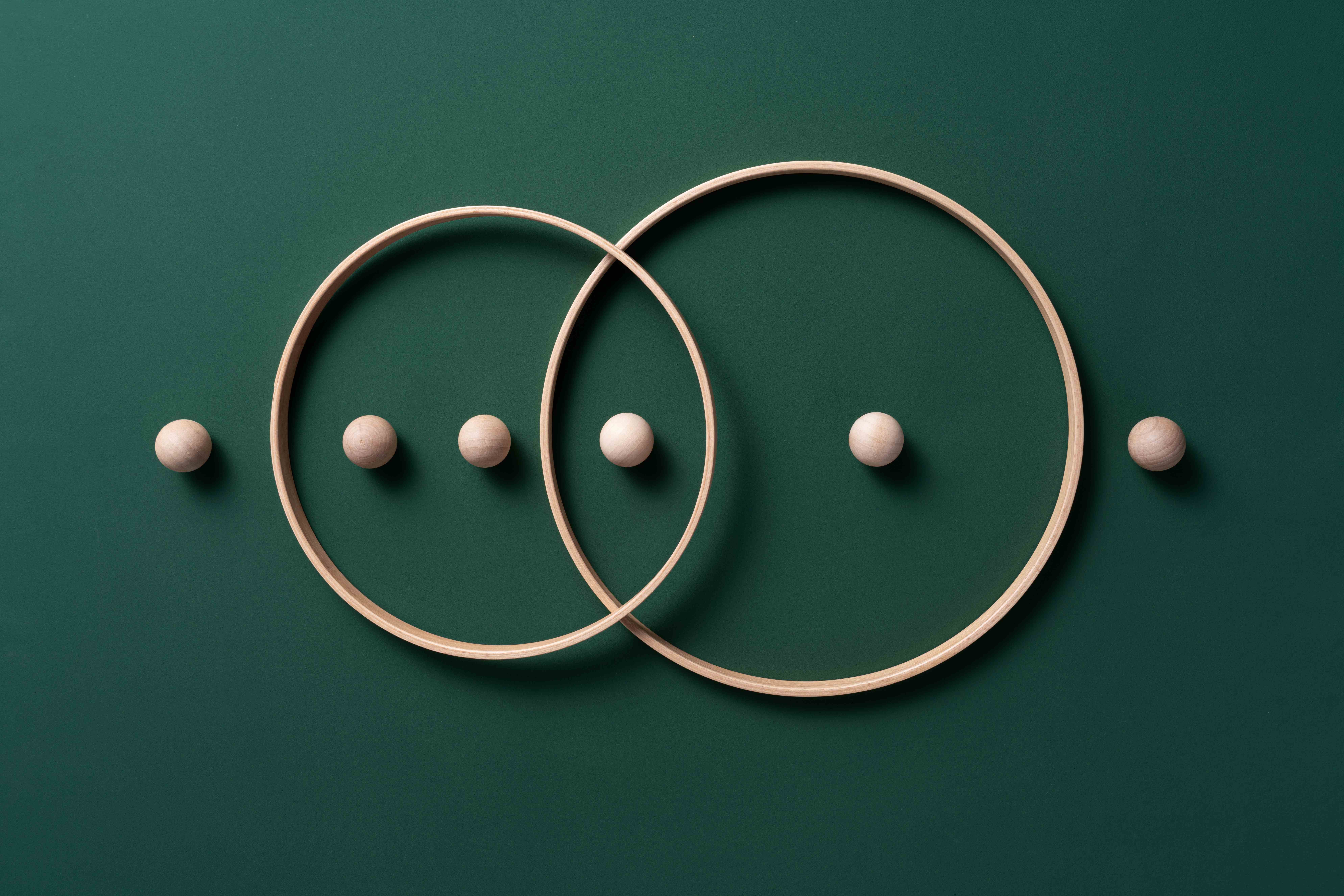 Bild von sich kreuzenden Ringen mit Kugeln auf grünem Hintergrund.