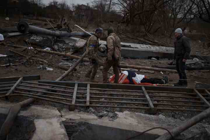 Le corps d'un civil dont la cause du décès est inconnue repose sur une civière sur un chemin utilisé comme voie d'évacuation depuis Irpin à la périphérie de Kiev, en Ukraine, le samedi 12 mars 2022.  (AP Photo/Felipe Dana)