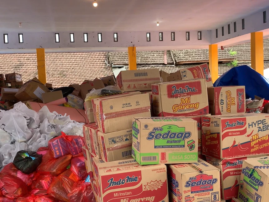 Des boîtes de nouilles instantanées sont empilées à côté de sacs en plastique contenant des produits de première nécessité pour les victimes de Semeru en Indonésie, décembre 2021.