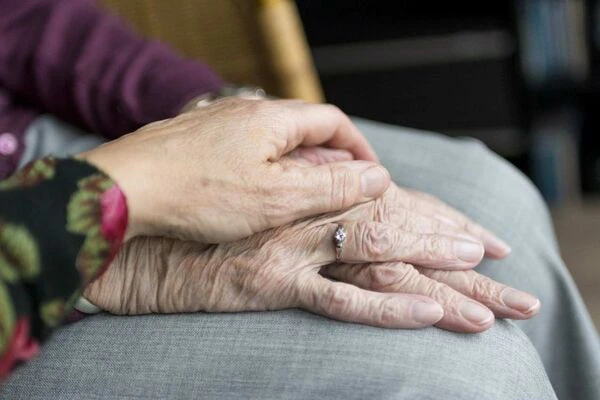 les mains d'une personne âgée tenues par une personne plus jeune donnent une image bienveillante