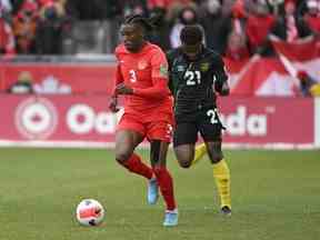 Le défenseur canadien Sam Adekugbe dribble le ballon loin de l'attaquant jamaïcain Javain Brown lors d'un match de qualification pour la Coupe du monde de la FIFA le dimanche 27 mars 2022 au BMO Field de Toronto.