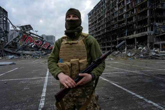 Un soldat se tient devant des bâtiments détruits à Kiev 