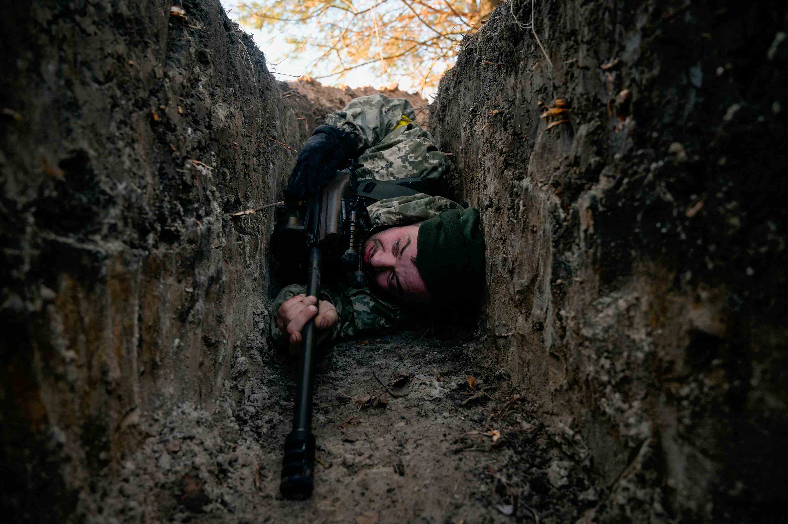 Un soldat ukrainien se cache d'une attaque par hélicoptère près de Demydiv, en Ukraine, le 10 mars. 