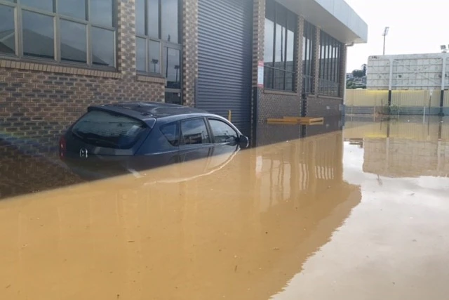 Une voiture submergée dans l'eau de crue sur une route.