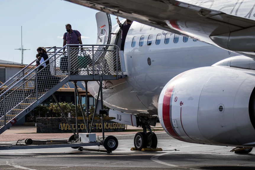 Une femme avec un bébé et un homme débarquent d'un vol Qantas à l'aéroport de Kalgoorlie-Boulder.   