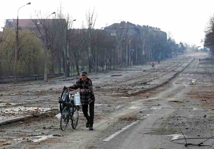 Un résident local marche à vélo le long d'une route près de l'usine sidérurgique d'Illich pendant le conflit Ukraine-Russie dans la ville portuaire méridionale de Marioupol, Ukraine, le 15 mars 2020.