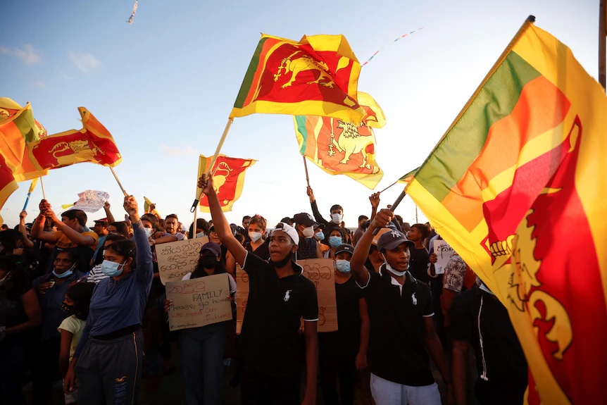 Un groupe de manifestants agite d'énormes drapeaux sri-lankais au-dessus de sa tête 