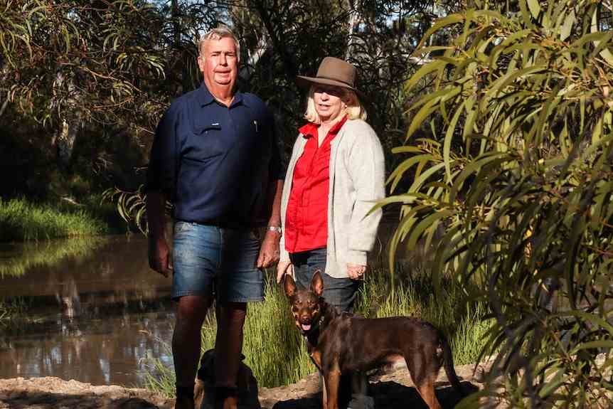 Glen et Barbara Beasley se tiennent avec leur kelpie rouge sur les rives d'un ruisseau à la ferme près de Chinchilla dans le sud du Queensland.