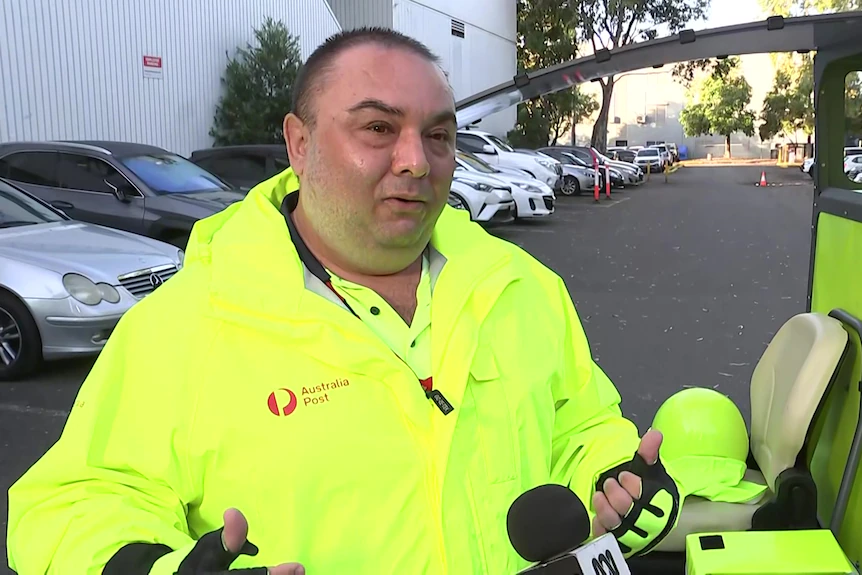 Le facteur en uniforme fluorescent se tient devant le postie trike