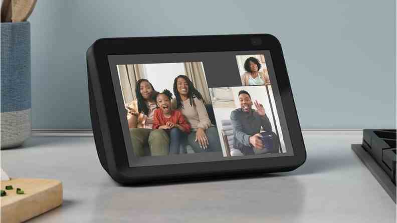 Famille souriante se connectant par appel vidéo sur une tablette intelligente sur le comptoir.