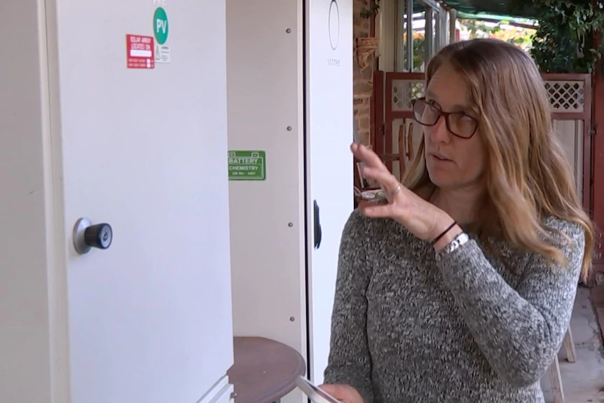 Une femme montre un placard sur son mur extérieur