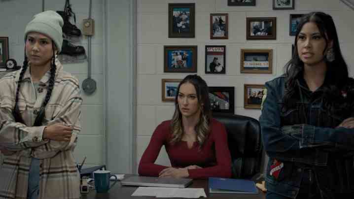 Keilani Elizabeth Rose, Tasya Teles et Blair Lamora regardent la caméra à côté d'un bureau dans une scène de Shoresy.