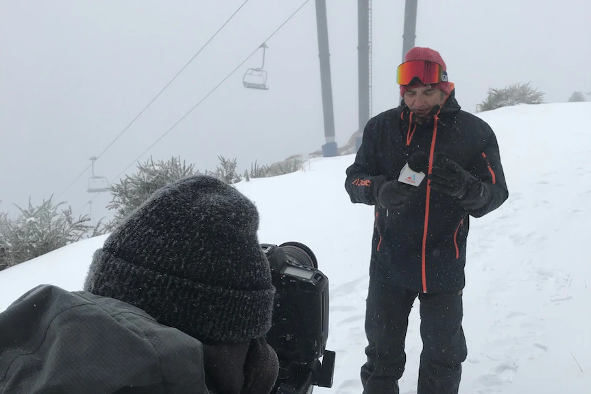 Un homme se tient à côté d'une caméra dans la neige.