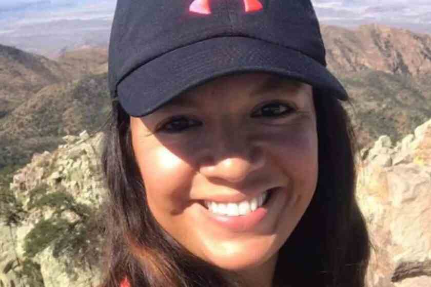 Un gros plan d'une femme dans une casquette de baseball, avec des montagnes en arrière-plan