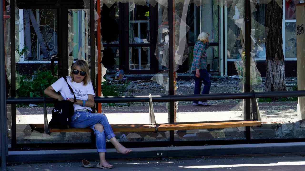Une femme est assise dans un arrêt de bus détruit à Marioupol