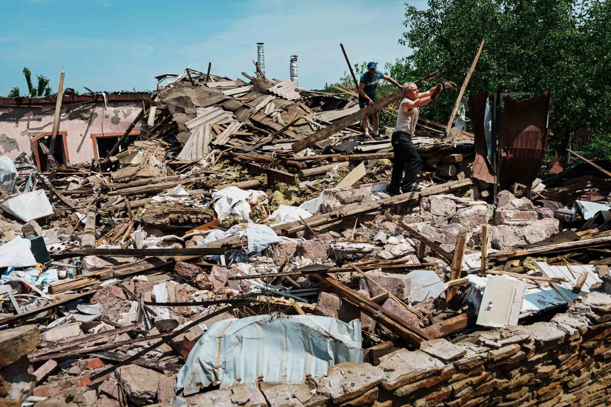 Des résidents locaux nettoient les décombres après qu'un attentat à la bombe a détruit une maison à la périphérie de Sloviansk, en Ukraine.