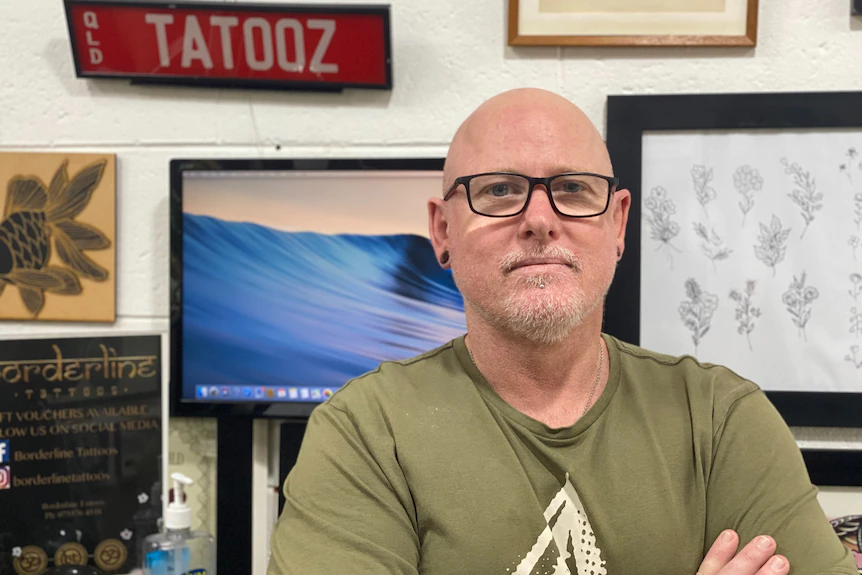 Un homme se tient derrière l'art dans un magasin de tatouage
