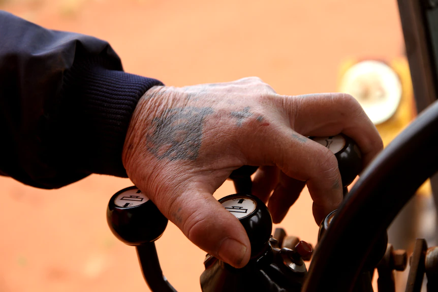 Une main tatouée tenant des engrenages dans un camion. 