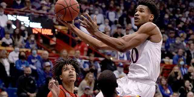 Ochai Agbaji du Kansas tire sur Elijah Olaniyi et Frankie Policelli de Stony Brook, à droite, pendant la première moitié d'un match de basket-ball collégial de la NCAA le jeudi 18 novembre 2021, à Lawrence, Kan.