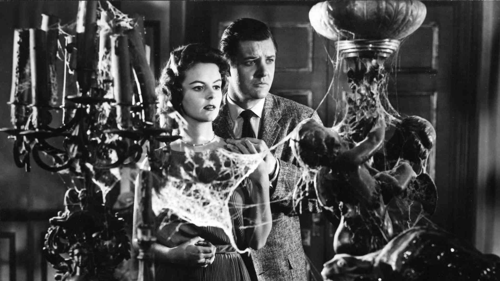 Un homme et une femme se tiennent devant de vieilles lampes recouvertes de toiles d'araignées.