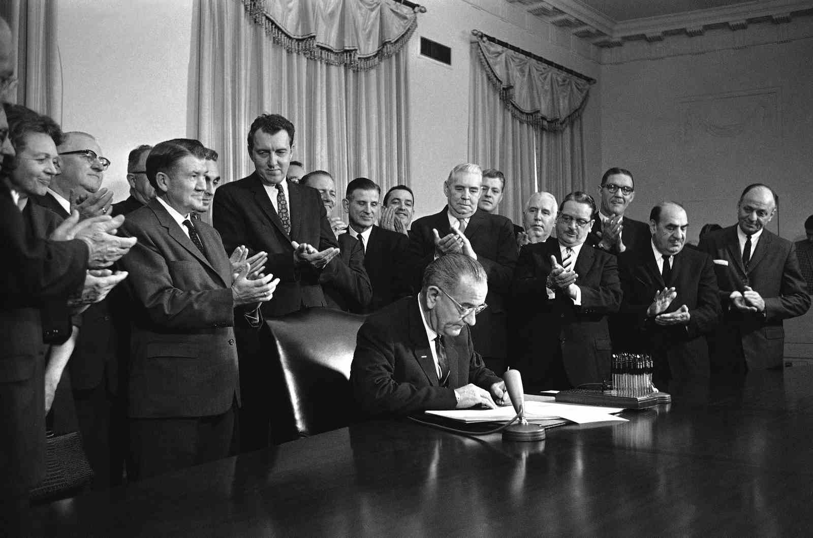une photo en noir et blanc du président signant un document