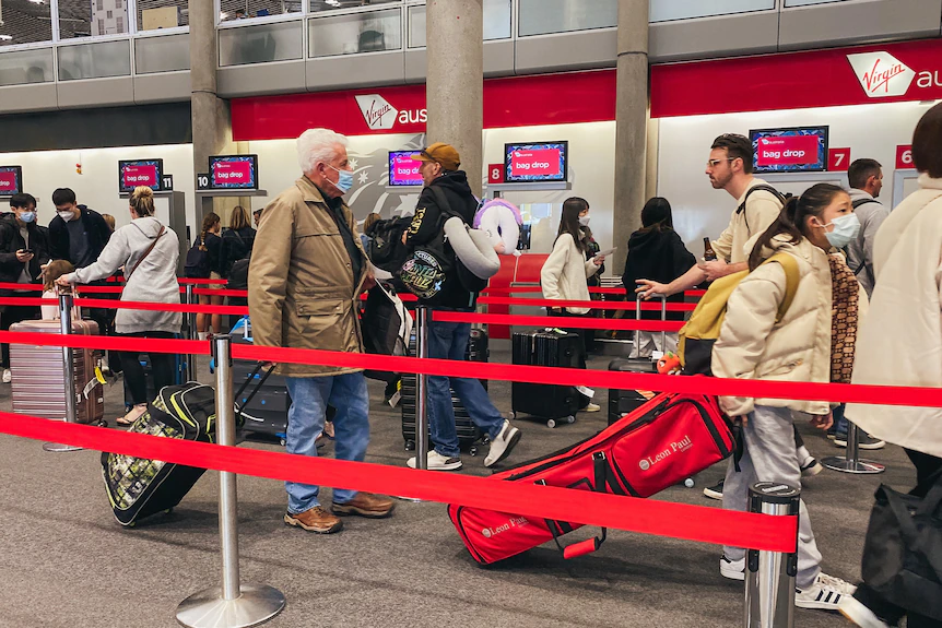 Les gens faisaient la queue pour s'enregistrer à l'aéroport de Brisbane avec des rubans rouges montrant les zones d'attente