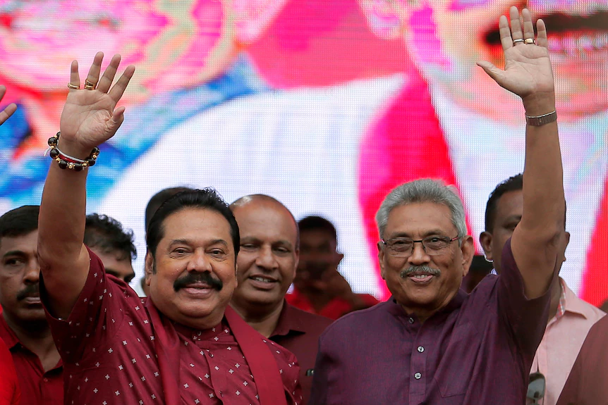 Gotabaya Rajapaksa dans une chemise violette salue avec son frère Mahinda Rajapaksa dans une chemise rouge et une écharpe agitant une foule