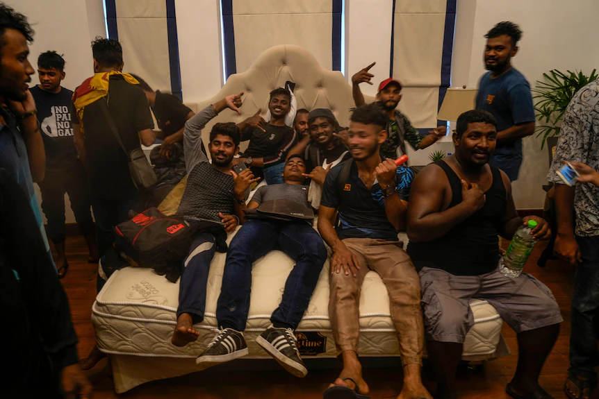 Une douzaine d'hommes sont allongés sur un lit dans le bureau du Premier ministre sri-lankais Ranil Wickremesinghe et font un geste de célébration.