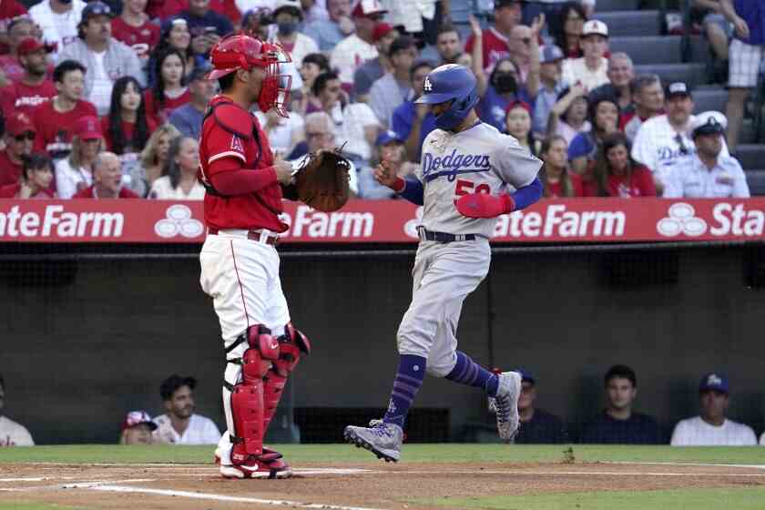 Mookie Betts des Dodgers marque sur le single de Freddie Freeman le 15 juillet 2022. Le receveur d'anges Kurt Suzuki est à gauche.