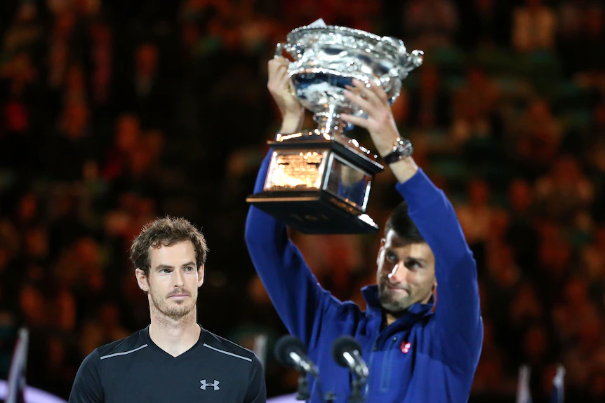 Andy Murray regarde Novak Djokovic de dos, qui soulève un grand trophée d'argent