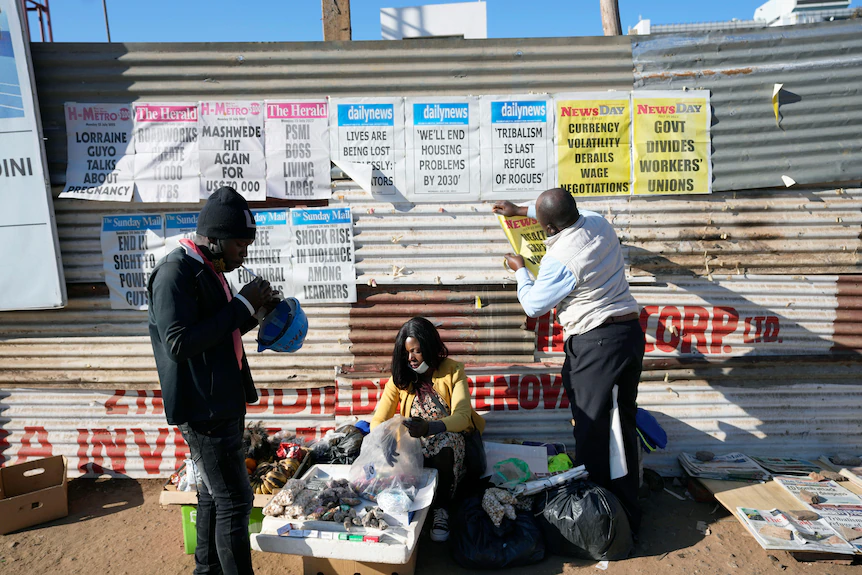 Un vendeur affiche des bannières de journaux alors qu'un vendeur se prépare à vendre dans une rue