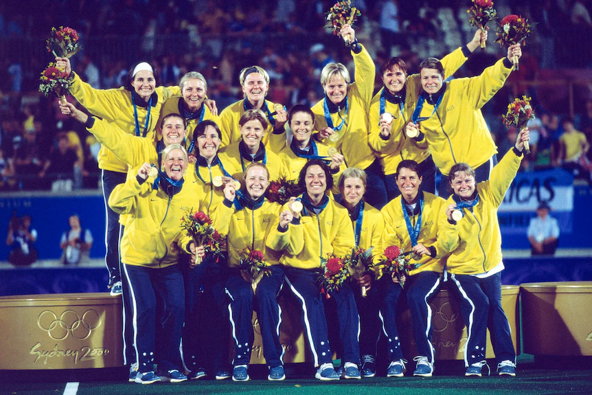 Les hockeyeurs roulent ensemble sur le podium, souriants, avec leurs médailles d'or et leurs bouquets de fleurs.