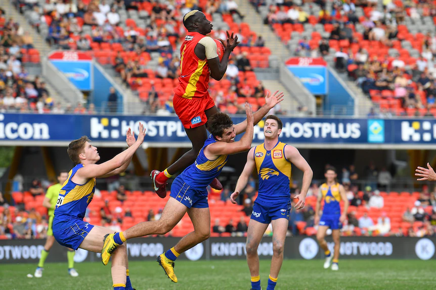 Un joueur de la Gold Coast AFL prend un point aérien au-dessus d'un adversaire de la côte ouest.