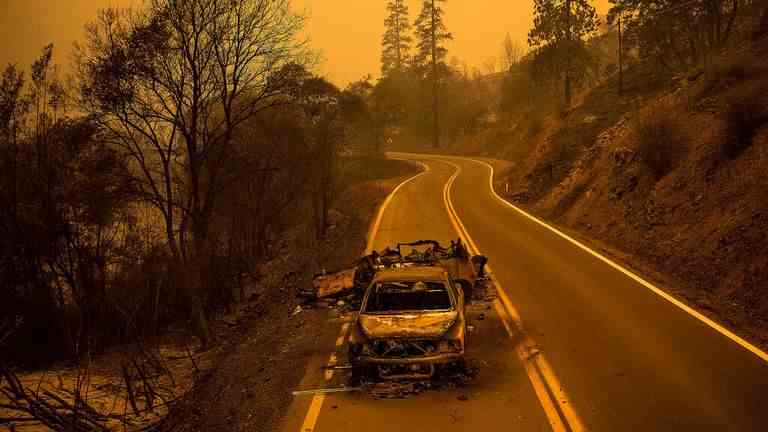 Une camionnette incendiée se tient sur la California Highway 96 dans la forêt nationale de Klamath, en Californie, le samedi 30 juillet 2022, alors que l'incendie de McKinney brûle à proximité.  (AP Photo/Noah Berger)