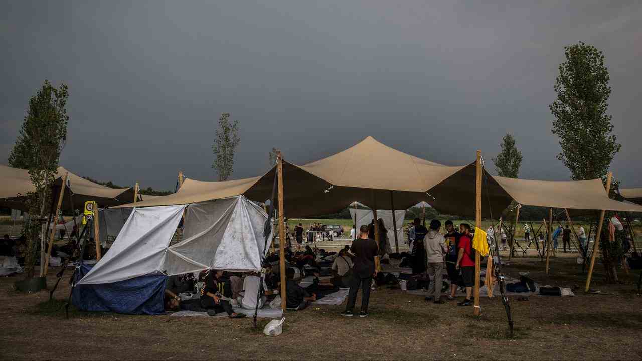 Des demandeurs d'asile attendent sur une pelouse devant le COA à Ter Apel.