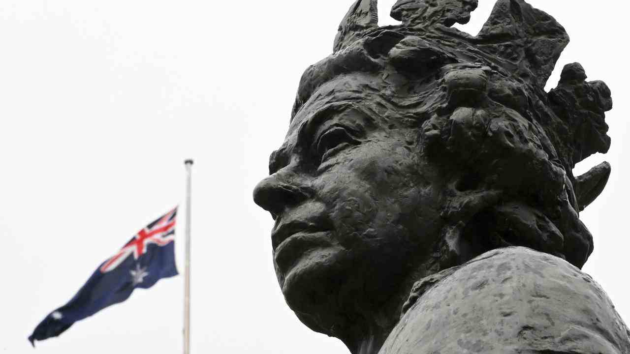 Le drapeau australien en berne derrière une statue de Sa Majesté la Reine au Parlement à Canberra, Australie