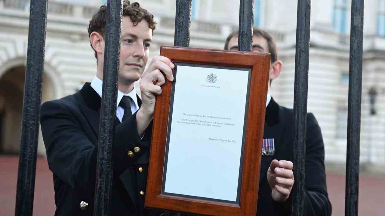 Les responsables du palais de Buckingham accrochent l'avis officiel de décès sur la porte.