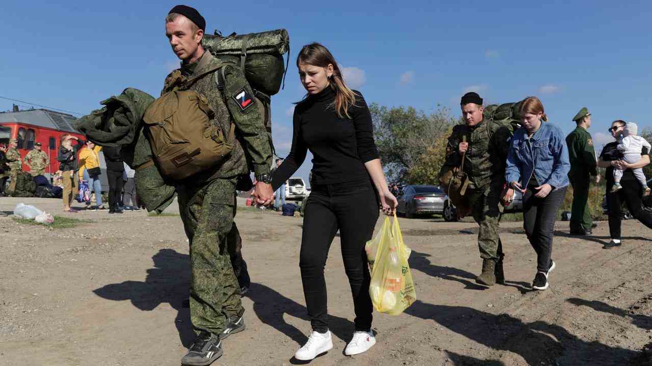 Les recrues russes marchent main dans la main avec leurs femmes.