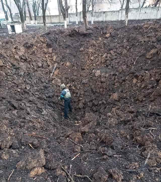 A member of the Ukrainian emergency services examines a large bomb crater at the Mariupol children's and maternity hospital - 9 March 2022